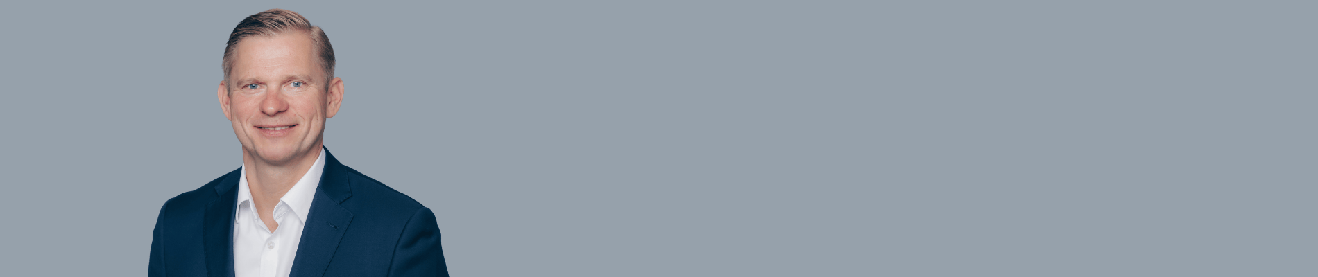 Smiling man in a suit on the left, with the "becker" logo in blue text on the gray background to the right.