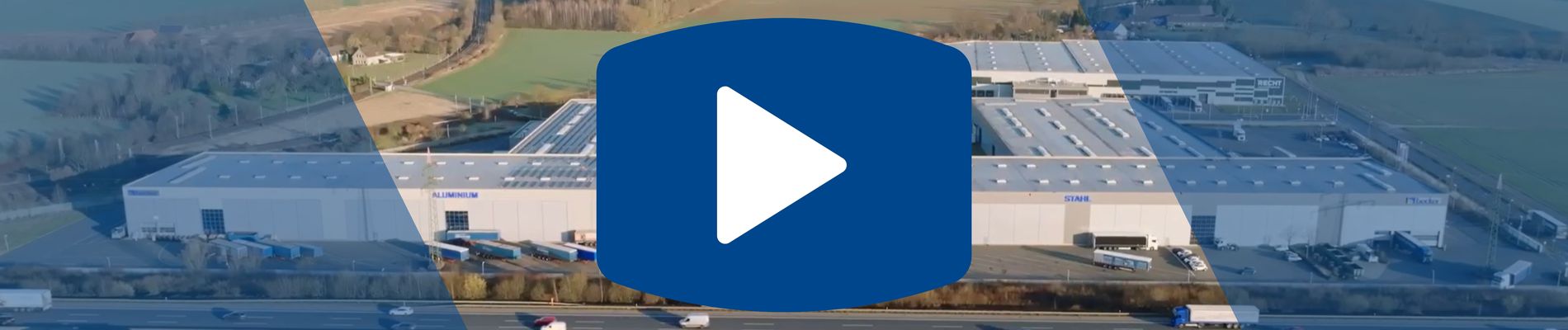 Aerial view of an industrial area with warehouses and roads, overlaid with a large blue play button icon in the center.