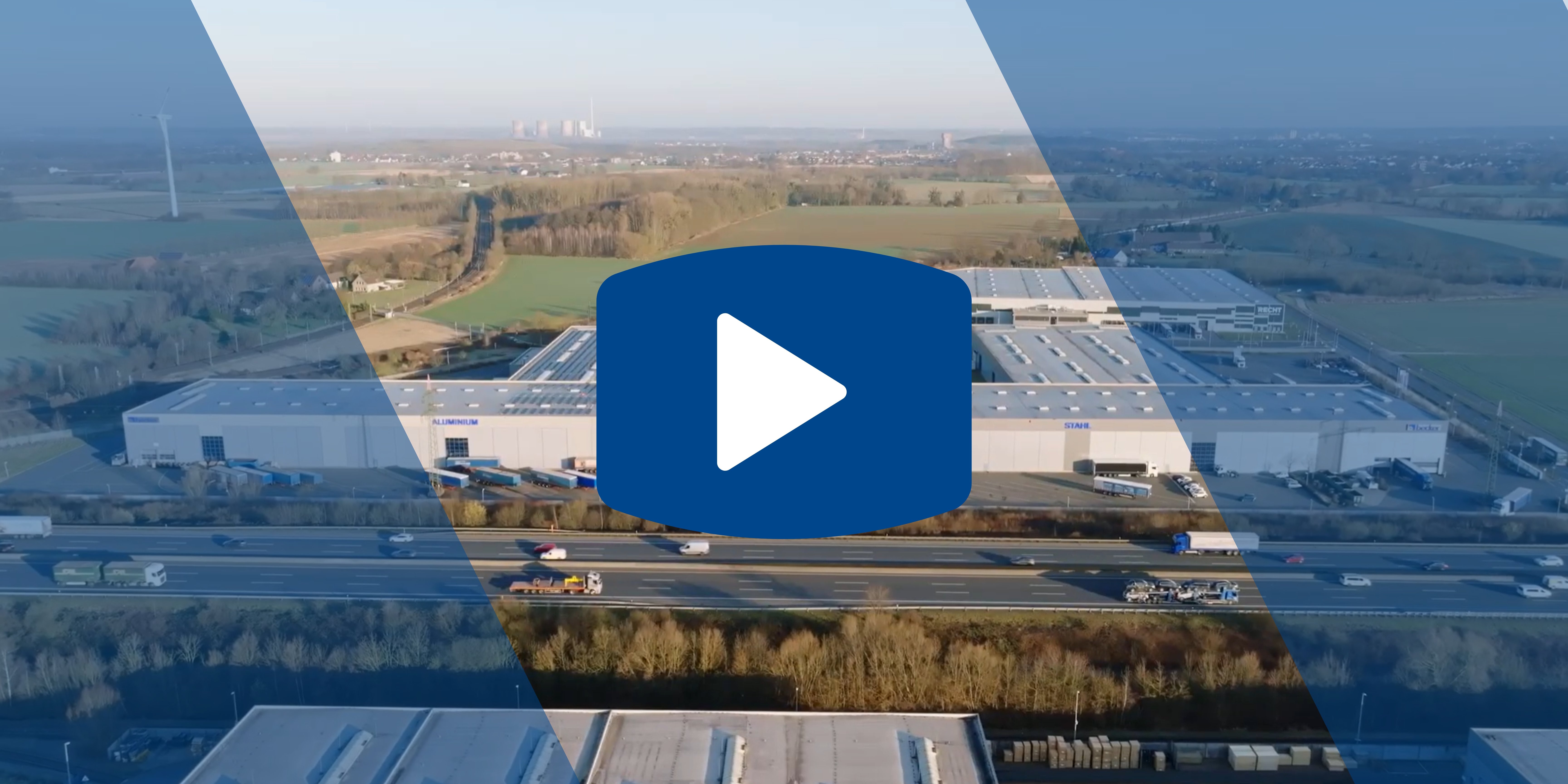 Aerial view of Becker - a large industrial warehouse near a highway, surrounded by fields, with a play button overlay in the center.